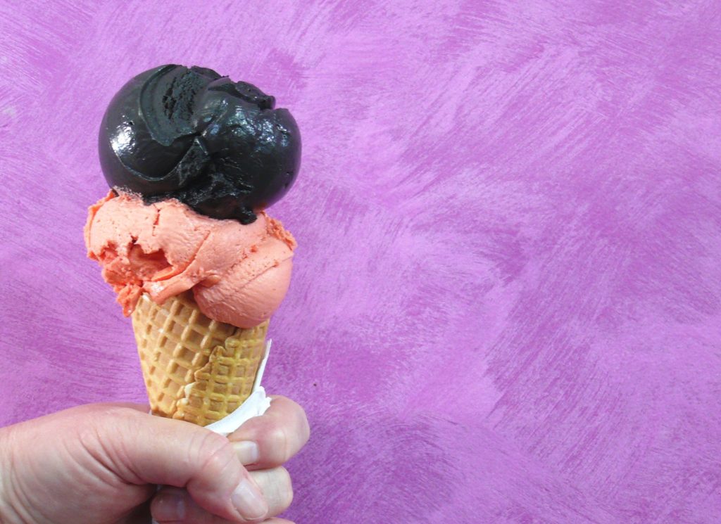 Blood orange sorbet paired with black magic gelato in a standard waffle cone.